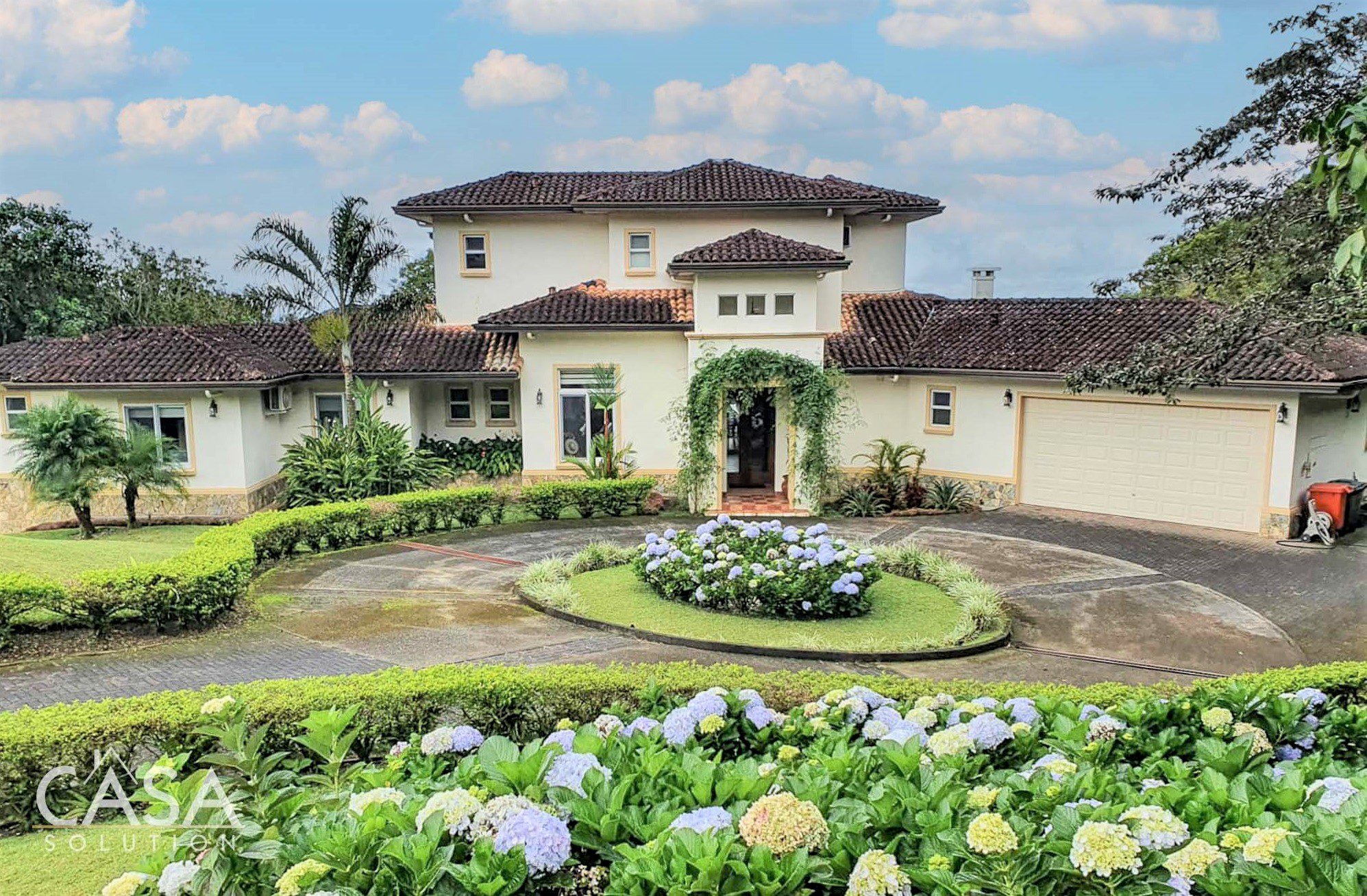 Facade of the property featuring a beautiful cobblestone driveway and adorned with vibrant flowers